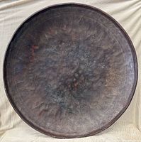 Front of round hand-hammered metal tray showing patina and hammer marks