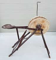 Full view of grinding wheel on tripod frame with seat