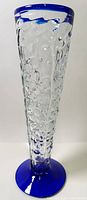 Full view of vase showing clear textured body with cobalt blue rim and base