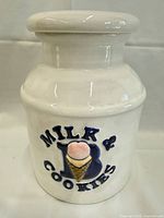Front view of white ceramic cookie jar showing Milk & Cookies design