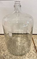 full view of clear glass carboy standing upright