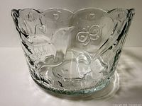 Front view of clear embossed glass bowl showing bird, heart and butterfly relief pattern