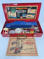 Open red metal Erector case showing contents and manual
