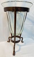 Side view of glass hurricane insert seated in wrought iron tripod stand