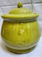 Front view of green crackle-glazed ceramic jar with lid
