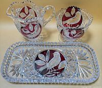 Creamer, sugar bowl and tray front view showing bird motifs and cranberry panels