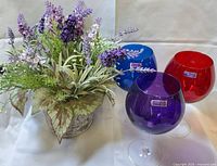Overall view showing artificial floral arrangement and three colored Marquis wine glasses