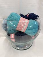Glass bowl holding multiple Patons Lace skeins teal and navy