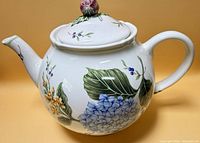 Right side view of porcelain teapot showing floral design and lid