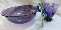 Three glass items: amethyst bowl, blue-violet ruffled vase, clear holder with blue flowers
