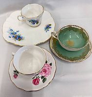 Three teacup and saucer sets displayed