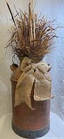 Full view of milk can with faux dried arrangement and burlap bow
