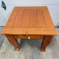 Front perspective of pine end table showing drawer, legs and finish wear