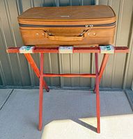Suitcase resting on wooden folding luggage rack