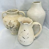 Group shot of three cream/white ceramic pieces: two vases and a pitcher