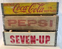 Front view of stacked Coca-Cola, Pepsi and Seven-Up crates showing logos and colors