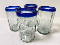 Four ribbed clear glass tumblers with cobalt rims standing