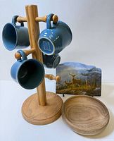 Mugs on wooden stand beside deer plaque and wood bowl