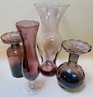 Group of four purple glass vases front view