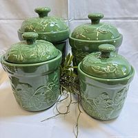 Four green ceramic canisters with lids, front and back view