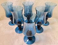Front view of six blue glass tulip goblets showing shape and color