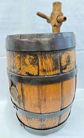 Front view of small wooden barrel, showing wood staves, metal bands, and spigot