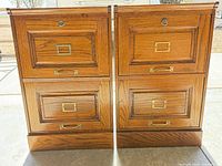 Front view of both oak two-drawer filing cabinets showing drawer fronts, brass hardware, and lock cylinders