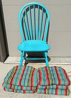 turquoise wooden Windsor chair with six stacked striped cushions