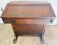 Closed desk showing drop-front top, dark stained wood, sled feet
