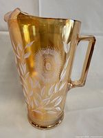 Full view of amber iridescent pitcher showing handle and white floral pattern