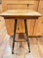 Full view of side table showing square top, turned legs, lower shelf