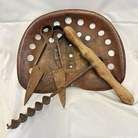 Overview showing tractor seat, auger bit, two dibbles, wooden-handled tool