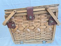 front view of wicker basket showing weave, leather clasp, wood handles