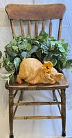 Full view of wooden chair holding pig bank and faux pothos