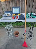 Overall lot showing table, LED light, toolbox, safety gear, rake, plant stands and pot