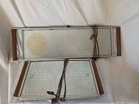 Top and underside view of two Salton warming trays showing aluminum tops, wooden handles and cords