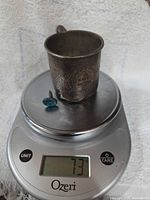 Cup and cufflink on scale showing 73 g total weight