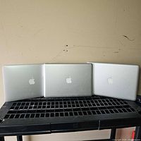 Three closed MacBooks showing exterior cases and logos