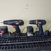 Both cordless drills with chargers and adapters lined up