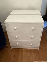 Front view of one white three-drawer dresser showing overall design and condition