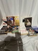 Front and back rows of eleven assorted paperback books displayed on white cloth