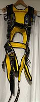 Full front view of yellow and black Guardian safety harness hanging on hanger