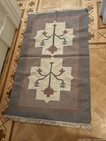Full view of kilim rug laid flat showing design, colors and fringe