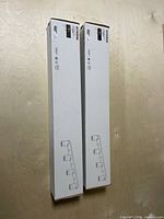 Two unopened IKEA NYMÅNE track light boxes standing vertically