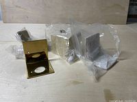 Four brass bottle brackets in plastic packaging with mounting screws