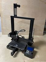 Full view of assembled Creality Ender 3 printer including frame, print bed, hotend, control box and filament holder mount