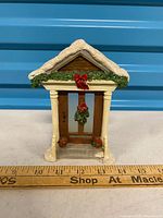 front view of polystone Christmas door candle holder showing wreath, columns, roof with snow