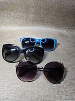 All three sunglasses displayed: blue rectangular, black cat-eye, round rose-gold