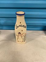 Front view of ceramic bottle showing “Santa’s milk” text and snowman graphic
