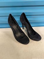 Full view of both Tory Burch suede pumps standing side by side